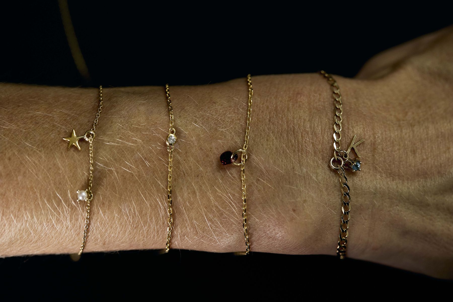A wrist wearing fine gold charm bracelets